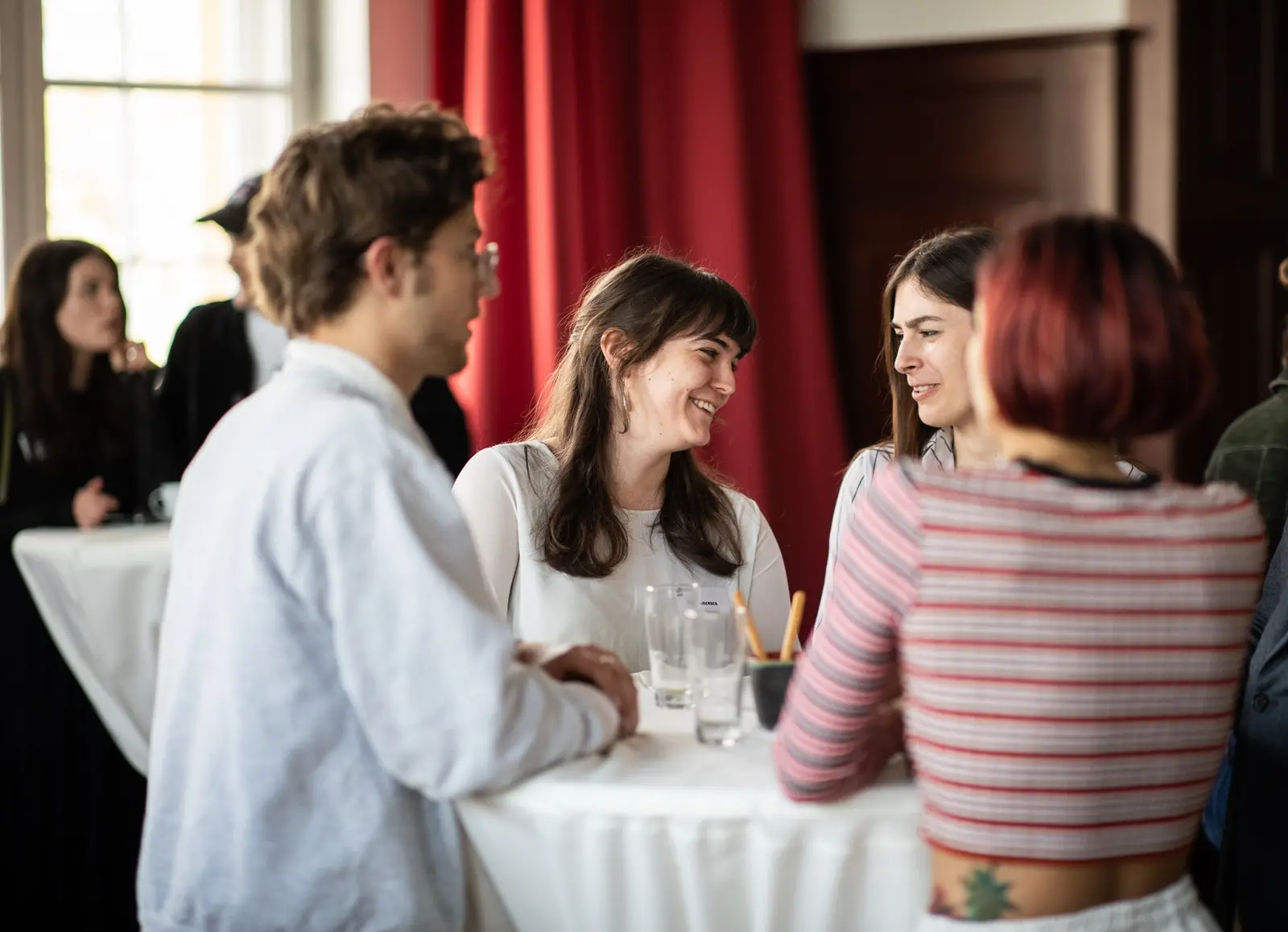 Studierende stehen an einem Stehtisch und unterhalten sich