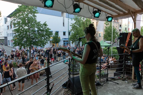 Campusfeast 2024 Eine Gitarristin steht auf einer Bühne, davor stehen viele Personen.