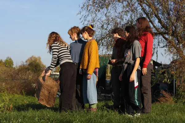 Studierende stehen in einer Reihe und müssen zusammen mit Pappe einen imaginären Fluss überqueren.