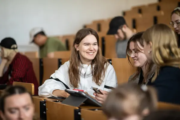 Studentinnen sitzen im Vorlesungssaal und unterhalten sich fröhlich