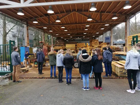 eine Gruppe Schüler*innen sieht sich eine Demonstration des Sägewerks an.