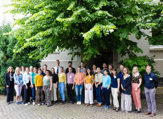 Eine Gruppe Menschen steht draußen vor einem Haus und posiert für ein Gruppenfoto.