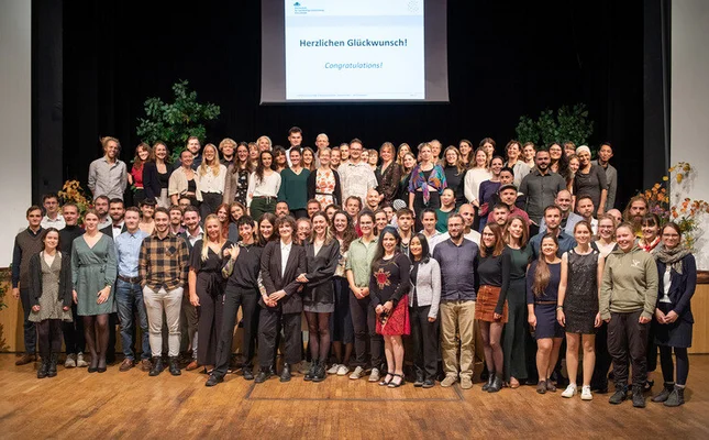 Gruppenfoto der Abschlussfeier 2023 Auf der Bühne im Haus Schwärzetal stehen die Alumni der Hochschule für nachhaltige Entwicklung Eberswalde aus dem Jahr 2023