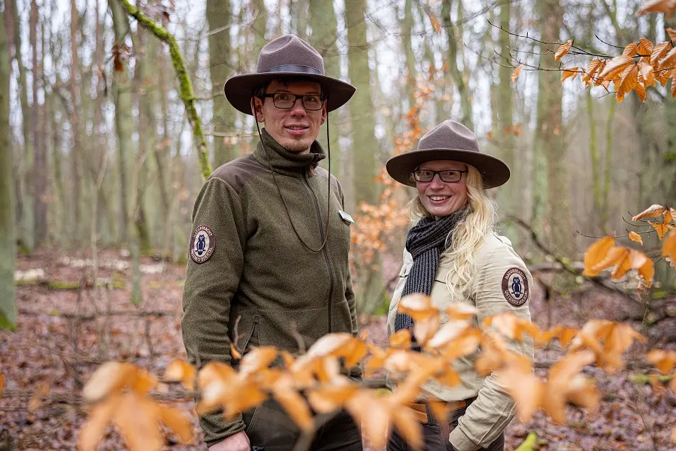 Ein Ranger und eine Rangerin posieren im Wald