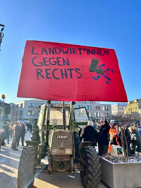 Ein Traktor hält ein Plakat mit der Aufschrift Landwirte gegen Rechts.