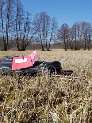 Eine Aktenmappe liegt auf einer schwarzen Tasche. Die befindet sich auf dem Grasboden eines Moores.