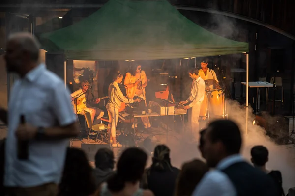 Band auf der Abschlussfeier 2022 Publikum vor der fünfköpfigen Band Phase Odyssey auf der HNEE Abschlussfeier im Jahr 2022 unter einem Pavillon vor der Waldcampus Mensa, mit viel Elektronik, Live Instrumenten, weißer Kleidung, gehüllt in Rauch